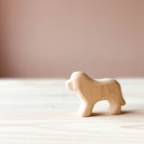 Ein Hund aus Holz steht auf einer Holzfläche und blickt seitlich nach vorne.