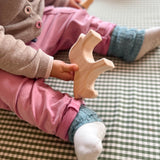 Ein sitzendes Baby hält das Holzpferd in einer Hand.