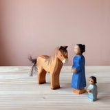 Drei kleine Holzfiguren zum spielen: Ostheimer Pferd braun steht mit Blick auf Ostheimer Figur Mutter und Figur kleines Kind.