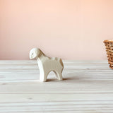 Die Ostheimer Spielfigur Schaf aus Holz steht auf einer Holzplatte und schaut nach links.