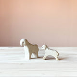 Die beiden Ostheimer Spielfiguren Schaf und Lamm, beide aus Holz stehen auf einer Holzplatte. Das Holzschaf schaut schräg nach links vorne und das Lamm sieht man von der Seite, es schaut nach links.
