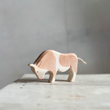 Der braune Stier von Ostheimer steht mit gesenktem Kopf seitlich nach links schauend auf einer hellen Holzfläche.