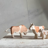 Man sieht die Ostheimer Kuhfamilie im Bild. Links steht der braune Stier mit gesenktem Kopf und schaut zur braunen Kuh und zum braun gefleckten Kälbchen.