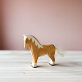 Es ist eine Ostheimer Spielfigur aus Holz zu sehen. Ein hellbrauner Hafllinger mit Baumwollschweif stehend, mit Blick nach links.