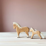 Zwei Spielfiguren aus Holz stehen hintereinander. Vorne ein Ostheimer hellbrauner Hafllinger, dahinter ein Haflingerfohlen, beide mit Blick nach links.