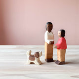 Die Ostheimer Spielfiguren Vater und Sohn stehen zueinandergedreht nebeneinander. Die Holzfigur kleiner Bernhardiner steht mit wedelndem Schwanz vor ihnen.