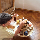 Ein Bub spielt mit "The Pendulum" von Grapat und schlichtet verschiedene Holzbausteine auf die Platte.