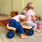 Zwei kleine Kinder sitzen auf dem Rutschauto aus Holz von Lautenbach, eines am Sitz, eines vor der Lenkung.