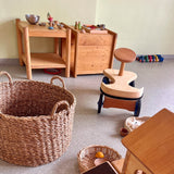 Das Holz-Rutschauto von Lautenbach steht in einem Raum mit Kinderspielsachen aus Holz und anderen Naturmaterialien und ist von hinten zu sehen.