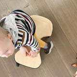 Ein Kleinkind setzt sich gerade auf das Holz-Rutschauto von Lautenbach.