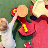 Ein Baby spielt mit kleinen gelben Holzautos auf dem roten Rutschauto von Lautenbach .