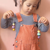 Ein Kind, das zwei Grapat Snowbuddy Christbaumanhänger in der Hand hält, die baumeln.