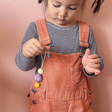 Ein Kind, das einen Grapat Snowbuddy Christbaumanhänger in der Hand hält, der leicht baumelt.