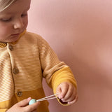 Ein Kind betrachtet den Aufhänge-Faden eines Grapat Snowbuddy Christbaumanhängers ganz genau.