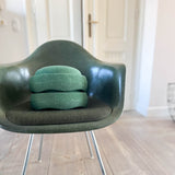 Zwei Stapelsteine Original in Dunkelgrün lübereinander gestapelt auf einem ebenso dunkelgrünen Schalenstuhl.