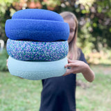 Der Stapelstein® Confetti Single Super Cool in einem Turm mit einem hellblauen und einem dunkelblauen Stapelstein, von einem Kind in die Kamera gehalten.