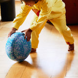 Ein Kind rollt den Stapelstein® Confetti Single Super Cool über den Boden.