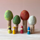 Vier Filzbäume für das Kleine Welt Spiel von Papoose Toys. Set mit vier Bäumen mit Holzstamm für alle vier Jahreszeiten, davor vier Grapat Nins in unterschiedlichen Farben.