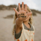 Ein Kind hält ihre mit "Dear Universe" beschriebene Hand in die Kamera.