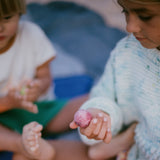 Ein Kind hält den Planeten Mond von Grapat Dear Universe in der Hand und betrachtet ihn ganz genau.