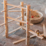 Das aufgebaute Grapat "Woodland" Bausteine-Set für Kinder mit zylinderförmigen Bausteinen und schmalen Holzleisten, sodass ein Bauwerk mit Brücken entsteht.