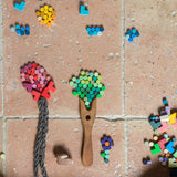 Grapat Mis, Match and Bloom Mini-Holzsteine als Landschaft mit Bäumen, Blumen, Sonne und Wolken auf dem Steinboden aufgelegt.