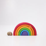 Der kleine Regenbogen von Grimms in den klassischen sechs Regenbogenfarben. Daneben liegt das Haus einer Weinbergschnecke zum Größenvergleich.
