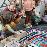 Kinder spielen mit der Grapat "Permanence Box" und verschiedenen Materialien, die daneben in Holzkästen bereit liegen.