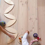 Ein Weg aus Blütenblätter Holzplatten von Grapat wird von zwei Kindern am Boden aufgebaut.