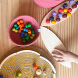 Die "Petal Platforms" Holzplatten von Grapat dienen einem Kind um allerlei bnte Mandala Steine aus Holz in verschiedenen Formen darauf zu stellen.