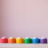 Die 24 Holzbecher "Nest Bowls" von Grapat in einer Linie nebeneinander, von vorne fotografiert. Die vier Becher in den verschiedenen Größen und Farbschattierungen sind jeweils ineinander gesetzt.