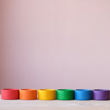 Die 6 größten Holzbecher in Regenbogenfarben der Grapat "Nest Bowls" nebeneinander aufgestellt.