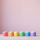 18 Holzbecher "Nest Bowls" von Grapat in einer Linie nebeneinander, von vorne fotografiert. Die Becher in den verschiedenen Größen und Farbschattierungen sind jeweils ineinander gesetzt.