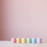 12 Holzbecher "Nest Bowls" von Grapat in einer Linie nebeneinander, von vorne fotografiert. Die Becher in den verschiedenen Größen und Farbschattierungen sind jeweils ineinander gesetzt.