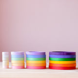 Die 24 Holzbecher "Nest Rings" von Grapat in einer Linie nebeneinander, von vorne fotografiert. Die vier Ringe in den verschiedenen Größen und Farbschattierungen sind jeweils aufeinander gesetzt.