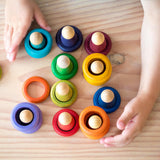 Grapat Rings Holzringe in verschiedenen Farben, darin stehen Grapat Nins Holzfiguren zum Spielen in den passenden Farben.