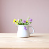 Das kleine Milchkännchen aus Emaille gefüllt mit frischen Wiesenblumen.