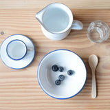 Frühstück im Montessori Kinderhaus: in einer Emailleschale liegen Heidelbeeren, daneben ein kleiner Holzlöffel, ein kleines Wasserglas und eine kleine Kanne zum selbständig befüllen.