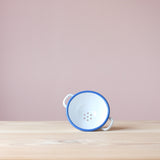 Das kleine Emaille Nudelsieb zum Spielen mit den zwei Henkeln auf die Seite gekippt, sodass man rein sehen kann.