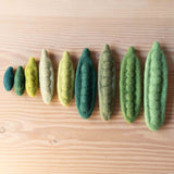 Papoose grüne Erbsenschoten aus Filz zum Bespielen liegen in einer Reihe der Größe nach sortiert.