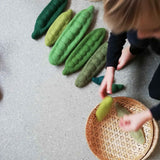 Ein Kind legt die grünen Erbsenschoten von Papoose in einen Korb.