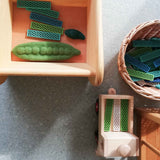 Blick von oben in Kisten, Kürbe und Holzlaster mit Bioblo Bausteinen und Papoose Erbsenschoten zum Spielen.