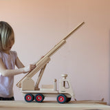 Ein Kind spielt mit dem Fagus Feuerwehr Fahrzeug, die Drehleiter wird gerade von ihm ausgefahren.