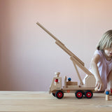 Die kleinen Holzfiguren von Fagus, wahrscheinlich Feuerwehrleute "steigen aus dem Feuerwehrauto aus" - das Kind stellt sie gerade daneben.