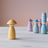 Eine der gelben Grapat Fancy Nins Spielfiguren mit farblich passendem Hut vorne, hinten stehen Grapat Fancy Nins in Blau- und Lilatönen.