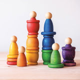 Grapat "Nins, Coins and Mates" Spielset für freies Spiel in Regenbogenfarben. Die Spielfiguren aus Holz, die Töpfchen und die bunten Holzplättchen sind zum Teil aufeinander gestapelt.