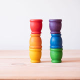 Die Grapat Mates Töpfchen aus Holz für freies Spiel sind zu je drei Farben aufeinander gestapelt.