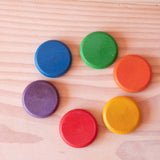 Die Grapat Coins Holzplättchen in den sechs bunten Regenbogenfarben liegen im Kreis.