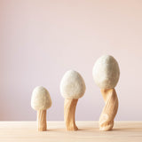 Die Filzbäume Winter mit weißer Baumkrone aus Filz und einem Stamm aus Treibholz in den drei verschiedenen Größen 23cm, 16cm und 28cm nebeneinander.