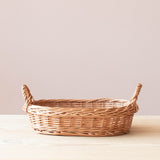 Ein flacher, ovaler Weidenkorb von Kokomoo mit zwei praktischen Tragegriffen für Spielzeugaufbewahrung.